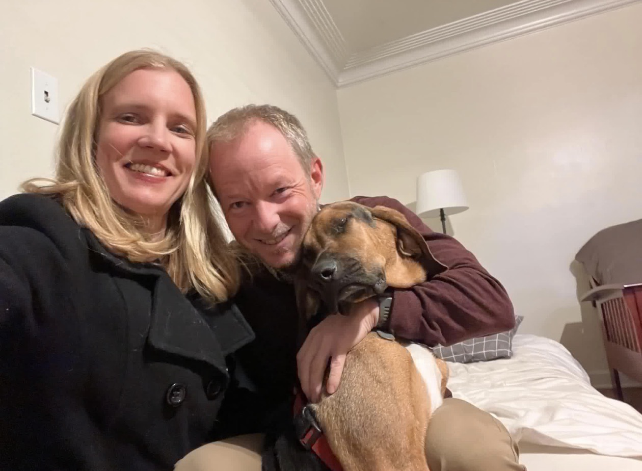 Kim and Eric smiling together with their dog
