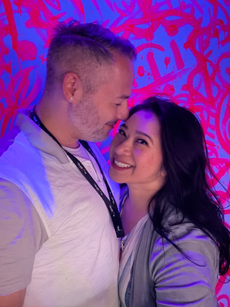 Stephanie and Shane together beneath vivid pink and blue light
