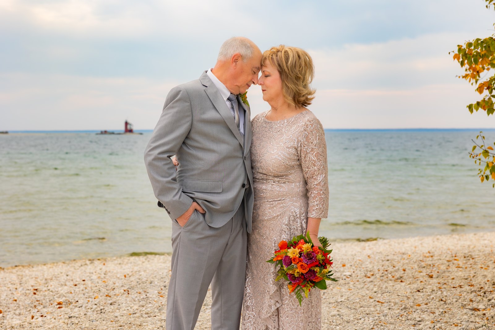 Brenda and Bob touching foreheads on the shore on their wedding day